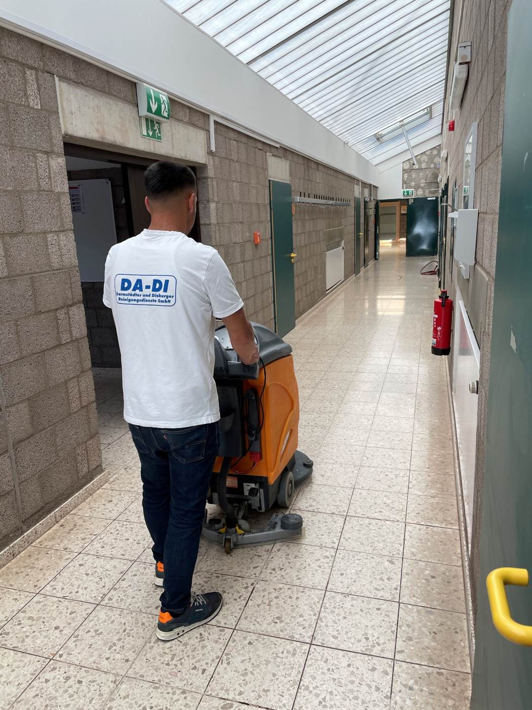 DA-DI Mitarbeiter mit Scheuersaugmaschine im Gewerbeflur